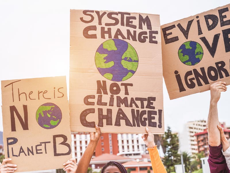 There's No Planet B. System Change Not Climate Change. Evidence Over Ignorance. Protestors holding signs.