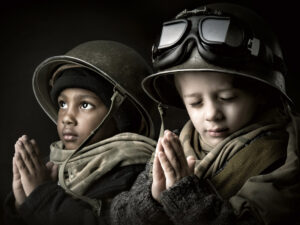 Photo of Two young boys dressed as soldiers with hands together as if in prayer