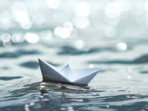 Paper Boat floating on sunny sea