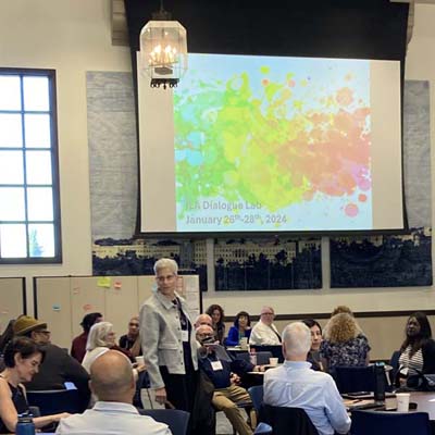 Photo of Cheryl Getz welcoming people to a day of dialogue