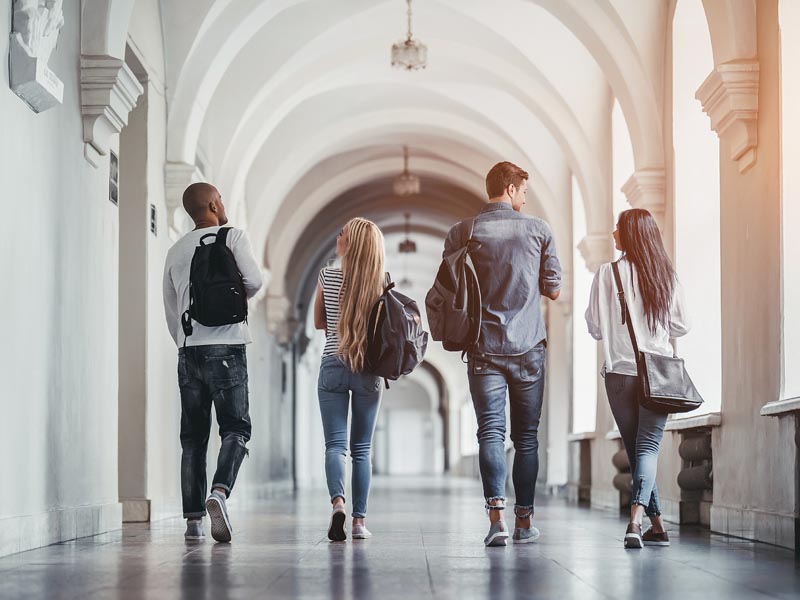 Photo of students walking down university hallway.