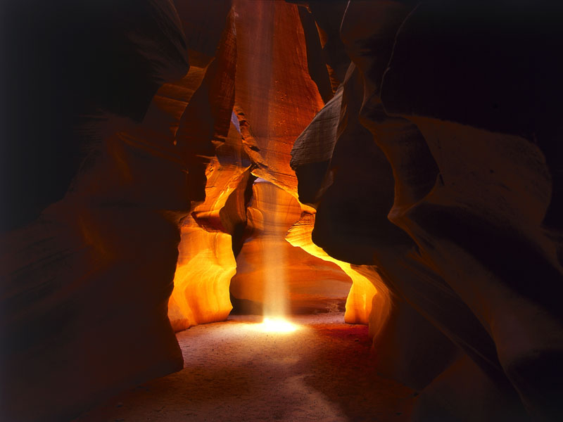 Photo of a shaft of light illuminating a cave system.