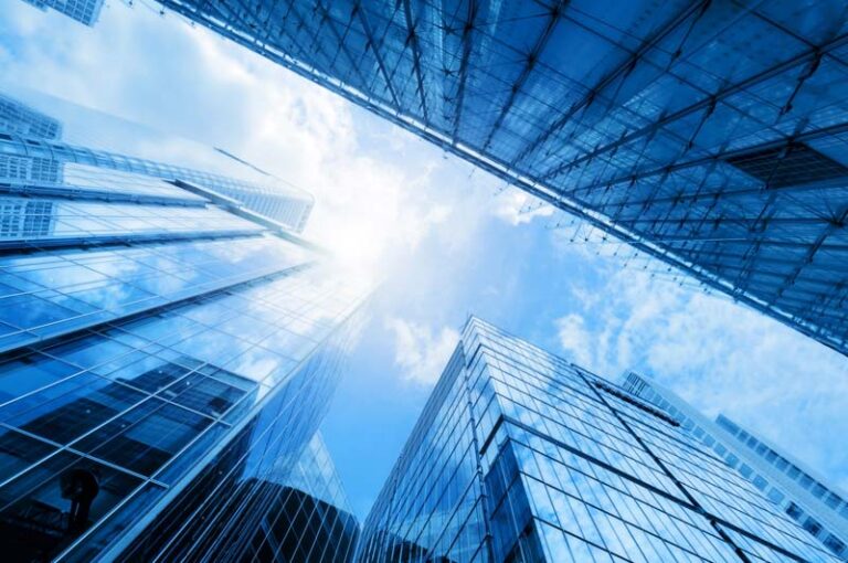 Image looking up to sky between glass sky scrapers